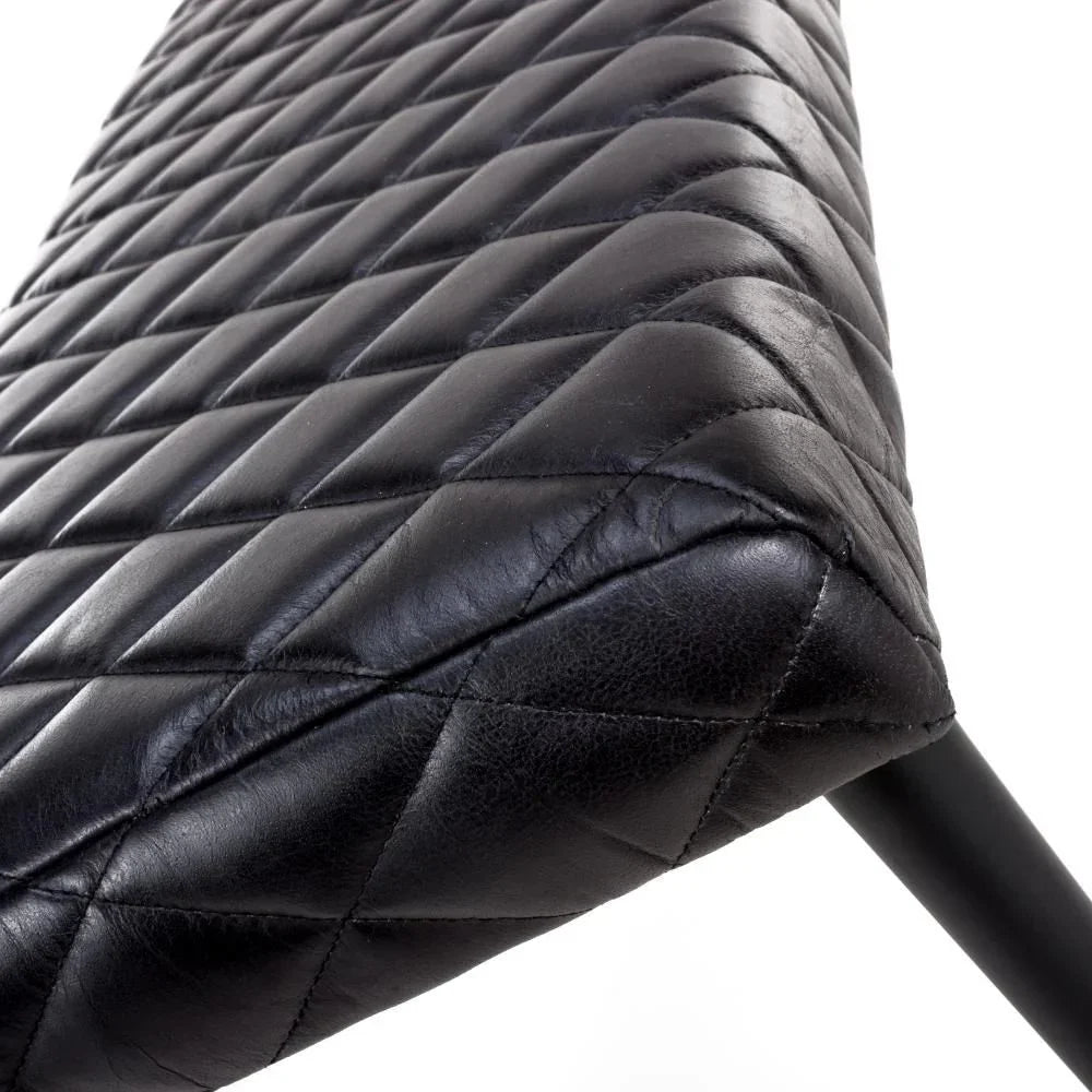 Black leather chair seat with diamond stitch pattern and visible metal leg