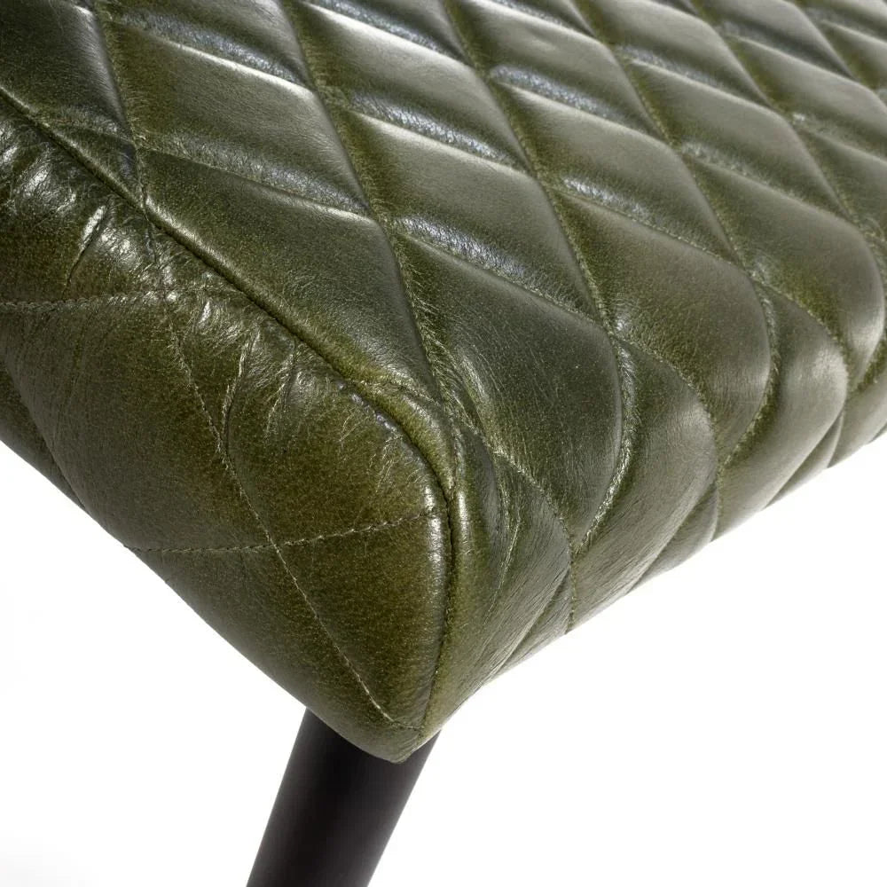 Green leather dining bench with diamond stitched seat and black legs, close-up view