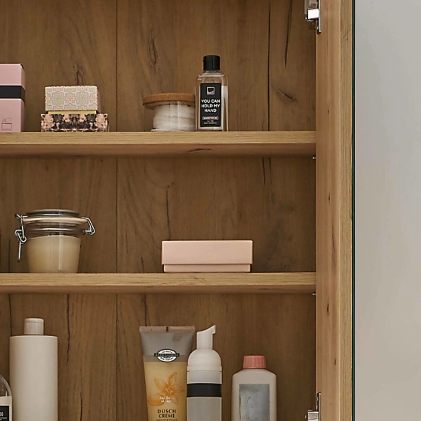 Oak bathroom cabinet shelves with skincare products, soap, jar candle and toiletries