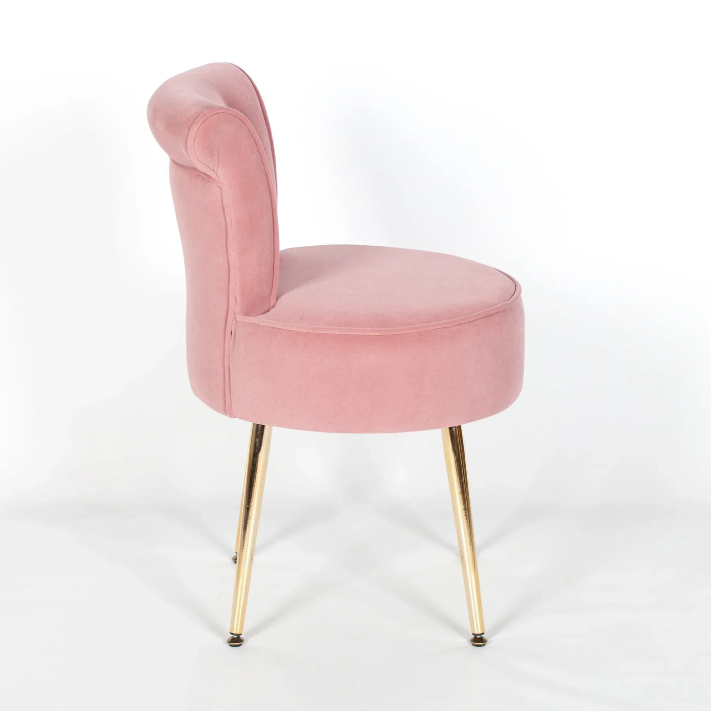 Pink velvet accent chair with gold metal legs, side angle view on white background
