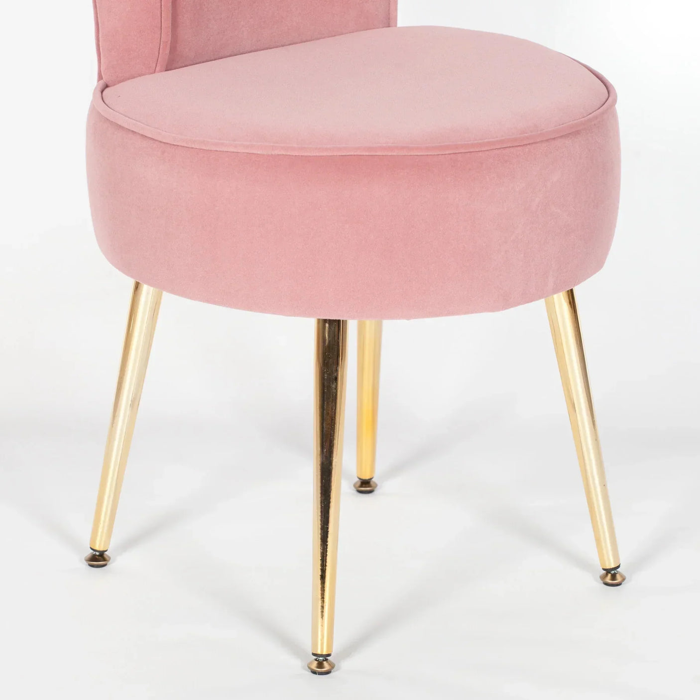 Pink velvet accent chair with gold metal legs, close-up view of seat and base