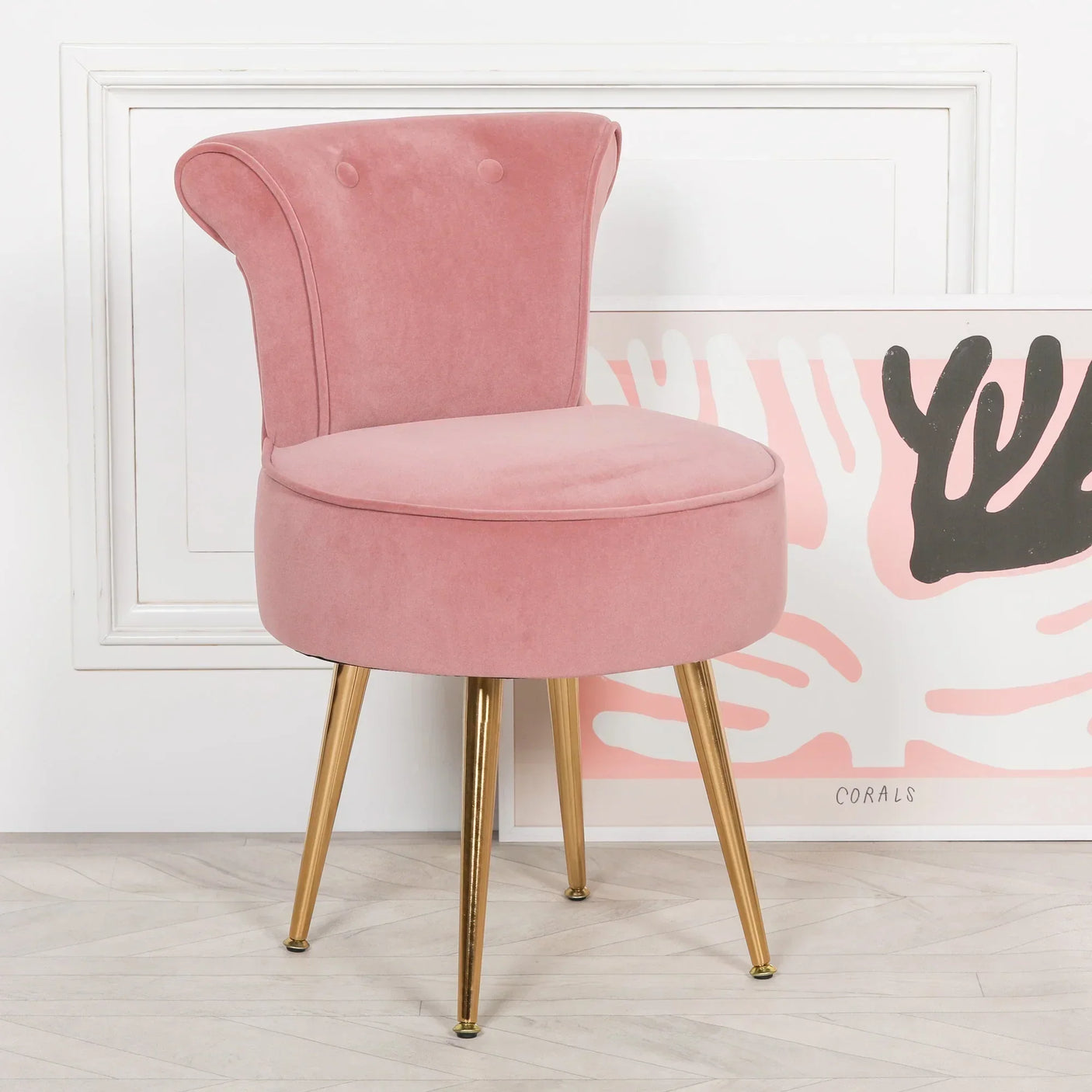 Pink velvet accent chair with buttoned backrest and gold metal legs on wooden floor