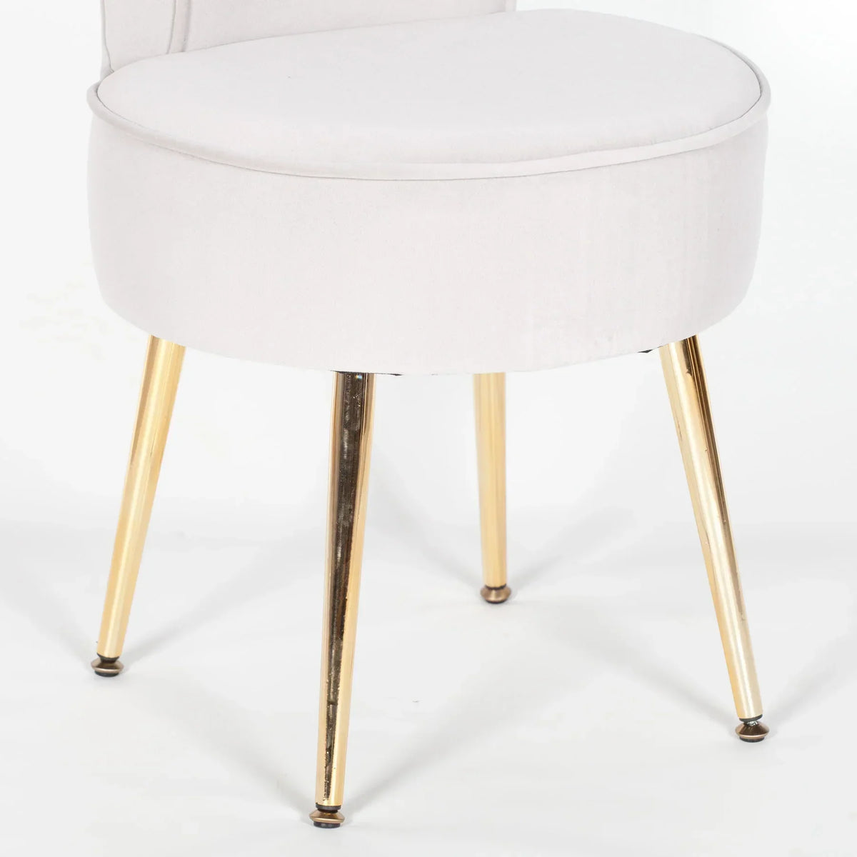 Velvet stool with gold metal legs and circular cushioned seat, close-up angle