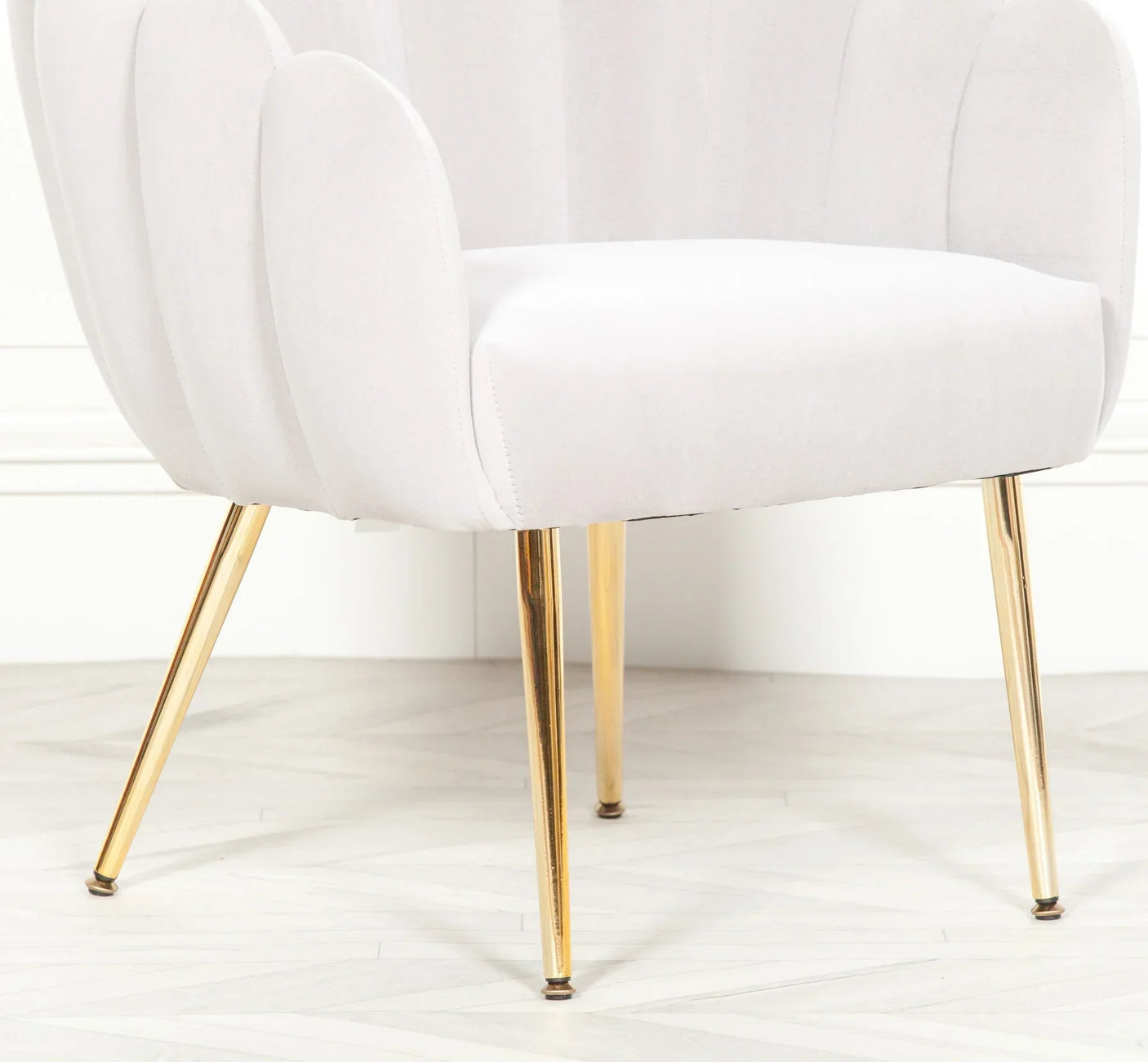 White velvet accent chair with gold metal legs on herringbone floor