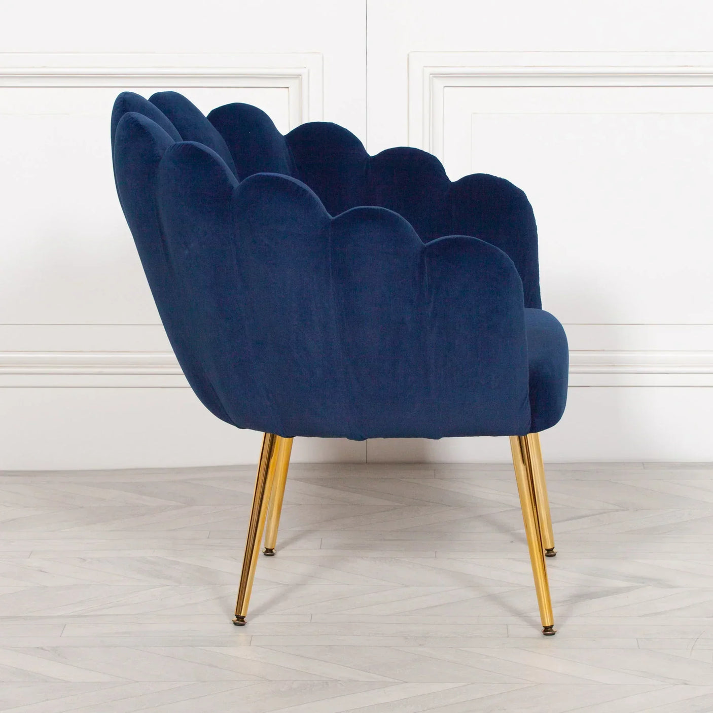 Navy velvet accent chair with scalloped back and gold metal legs side view