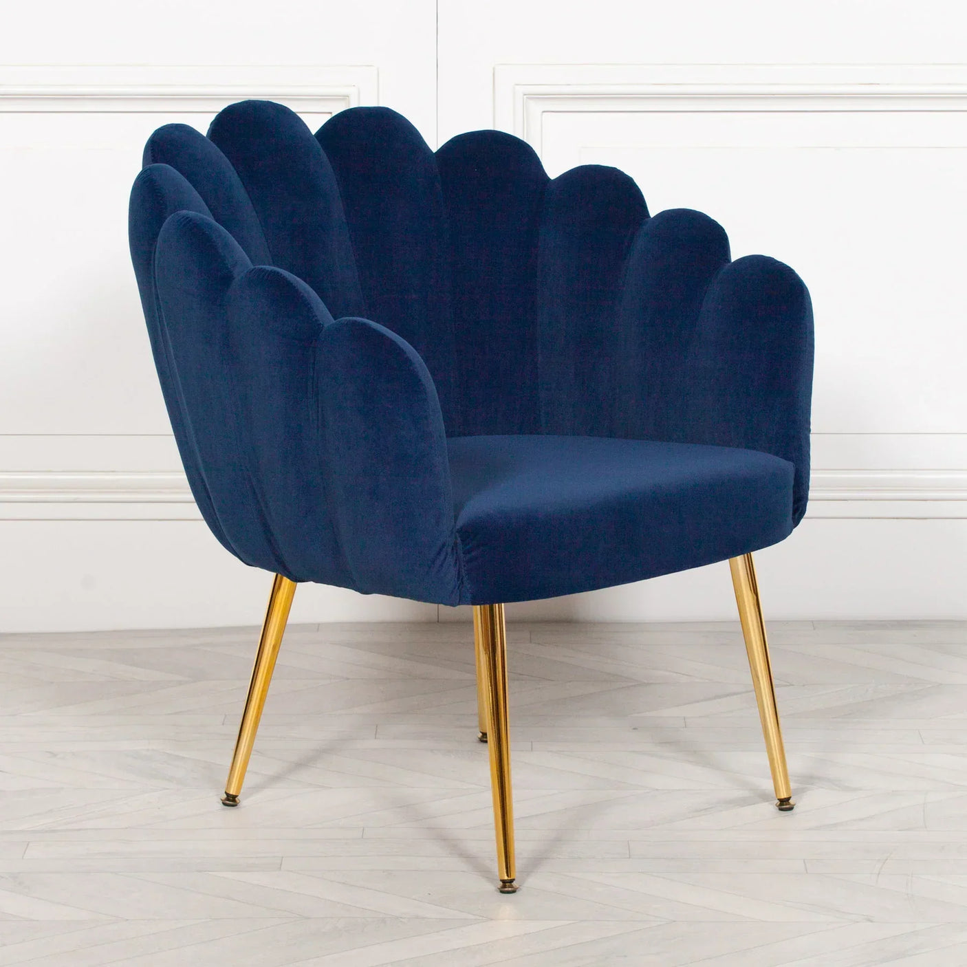 Navy velvet accent chair with scalloped backrest and gold metal legs on light wood floor