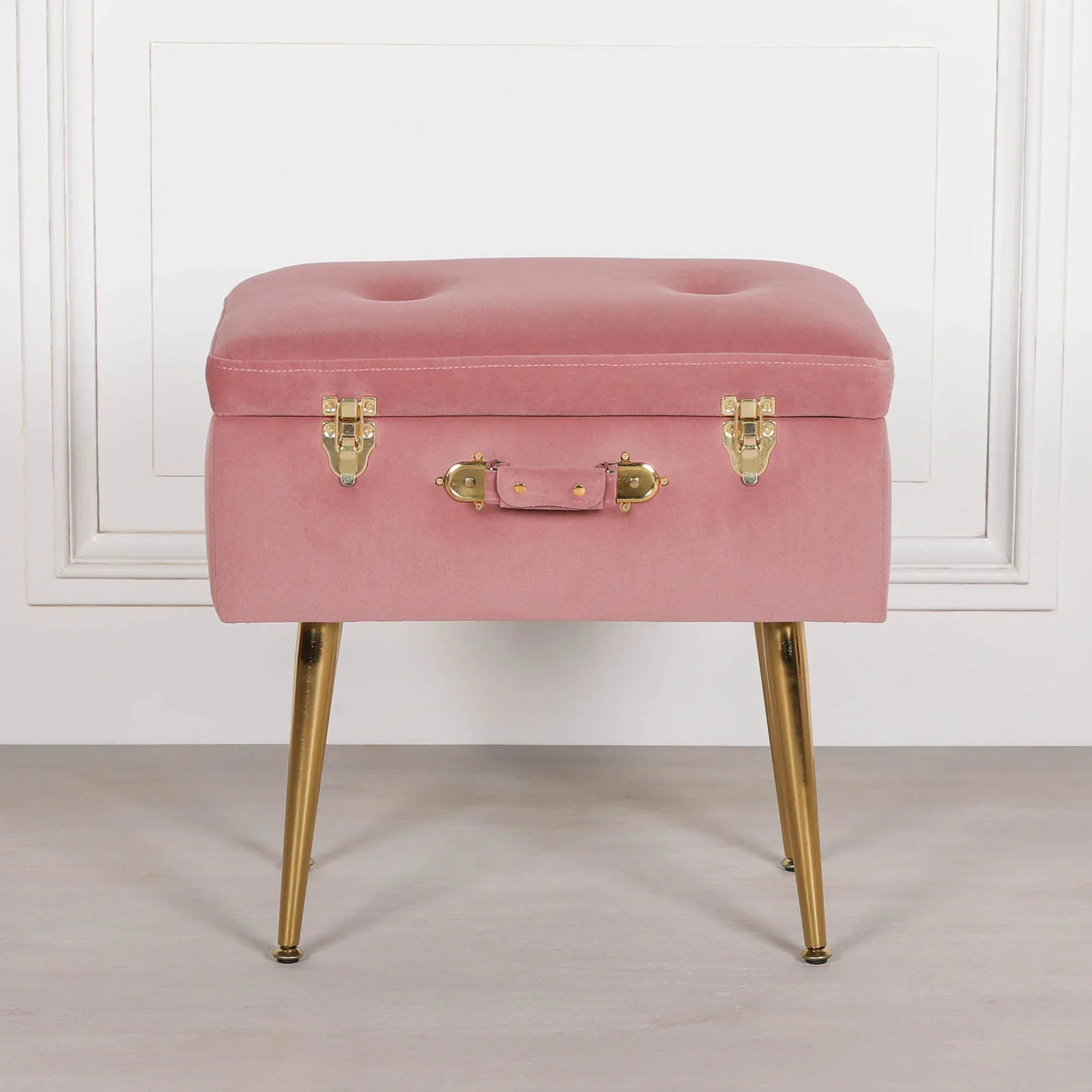 Pink velvet ottoman with gold metal legs and suitcase style latch front view