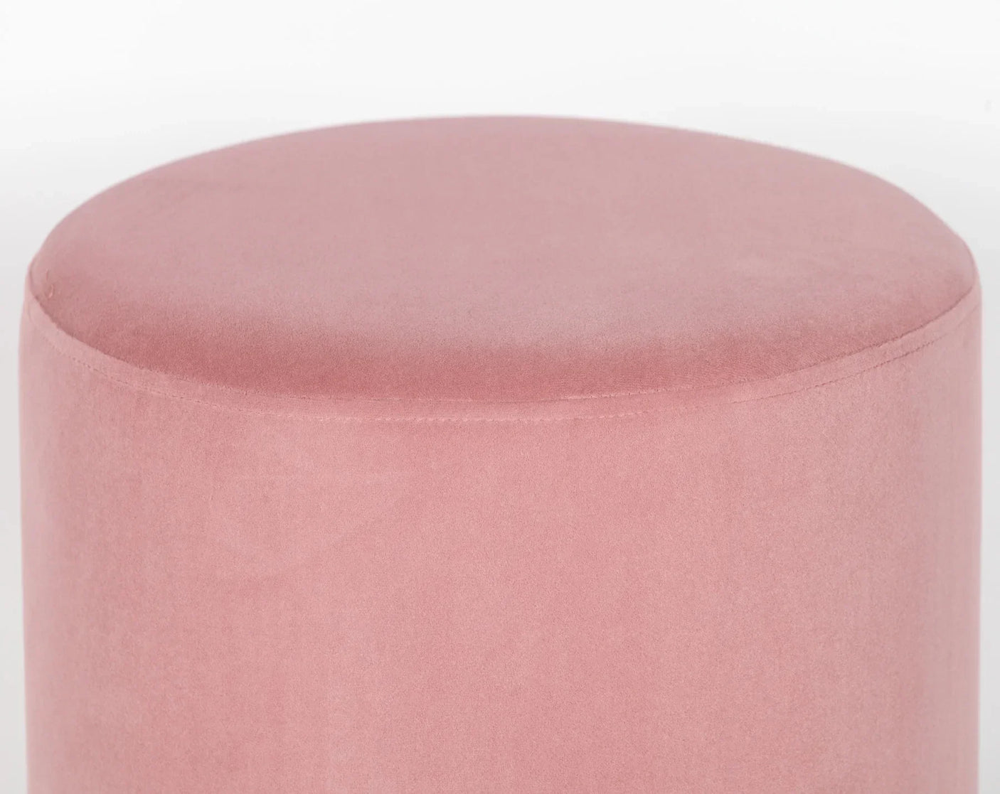 Pink velvet ottoman with round shape and seam detail against white background