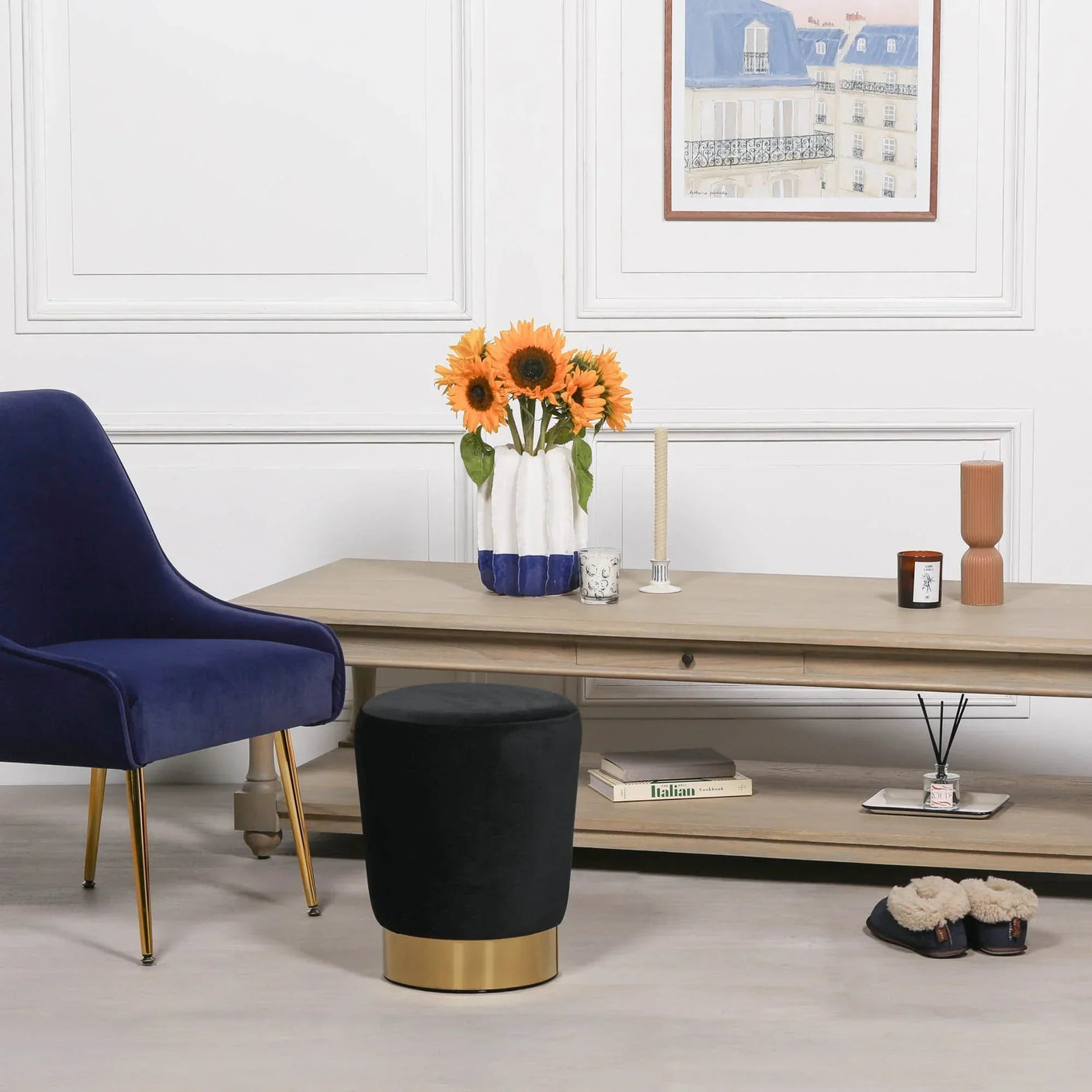 Black velvet footstool with gold base in living room beside wood coffee table and blue chair