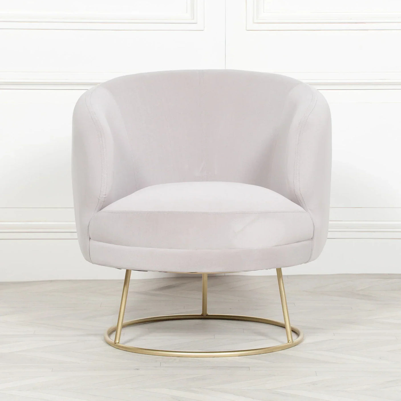 Light grey velvet accent chair with gold metal base on wooden floor