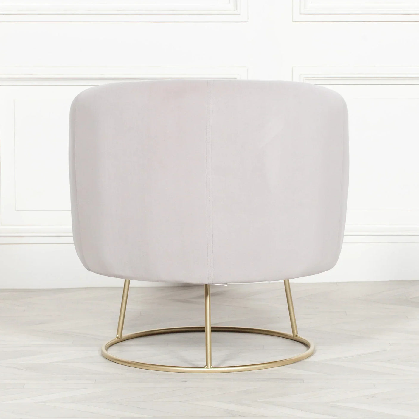 Back view of a velvet accent chair with gold metal base on light wood floor