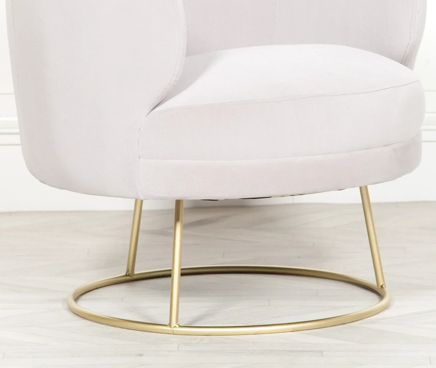 Light grey swivel chair with gold metal base on wooden floor