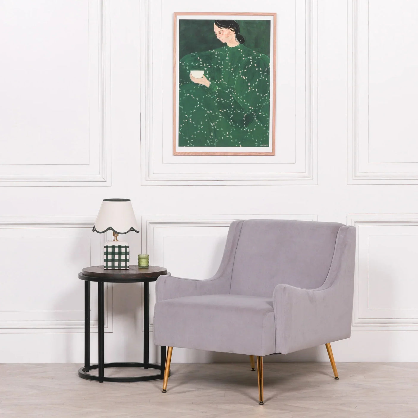 Grey accent armchair with gold legs beside round side table and lamp in modern living room