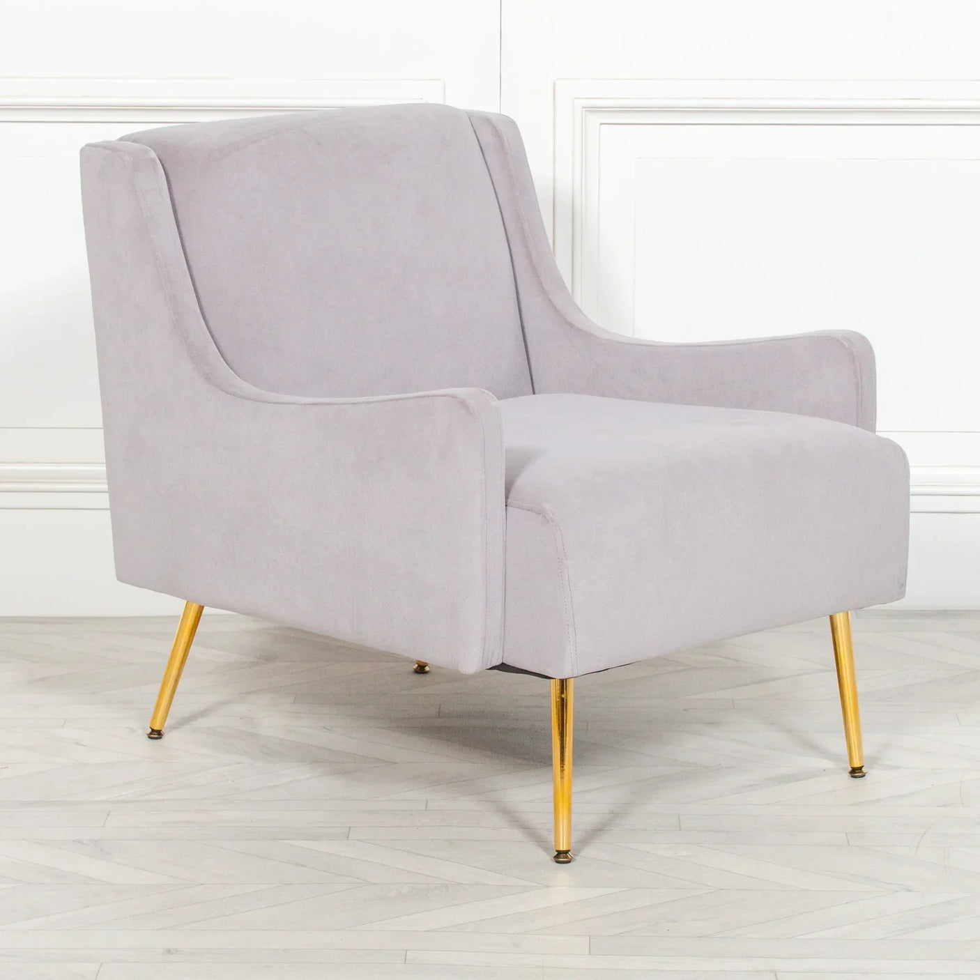 Light grey accent chair with gold metal legs on wooden floor