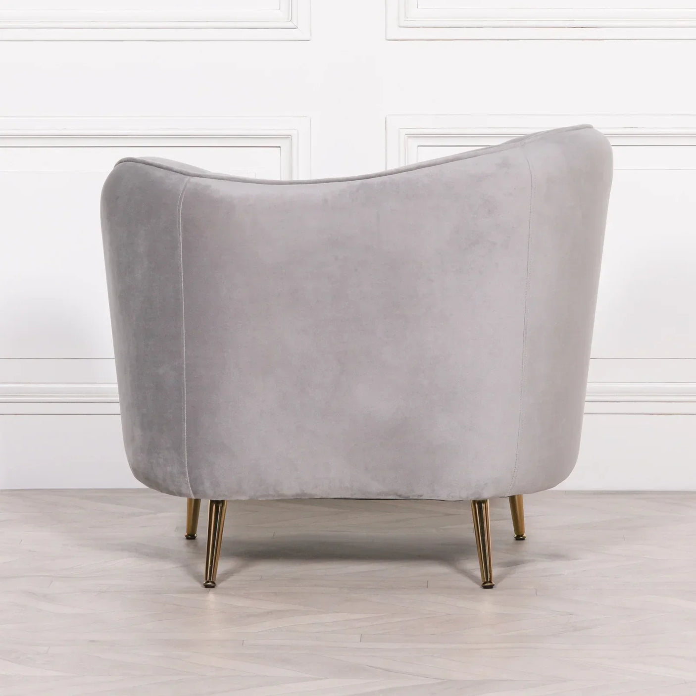 Light grey velvet accent chair with gold metal legs shown from the back
