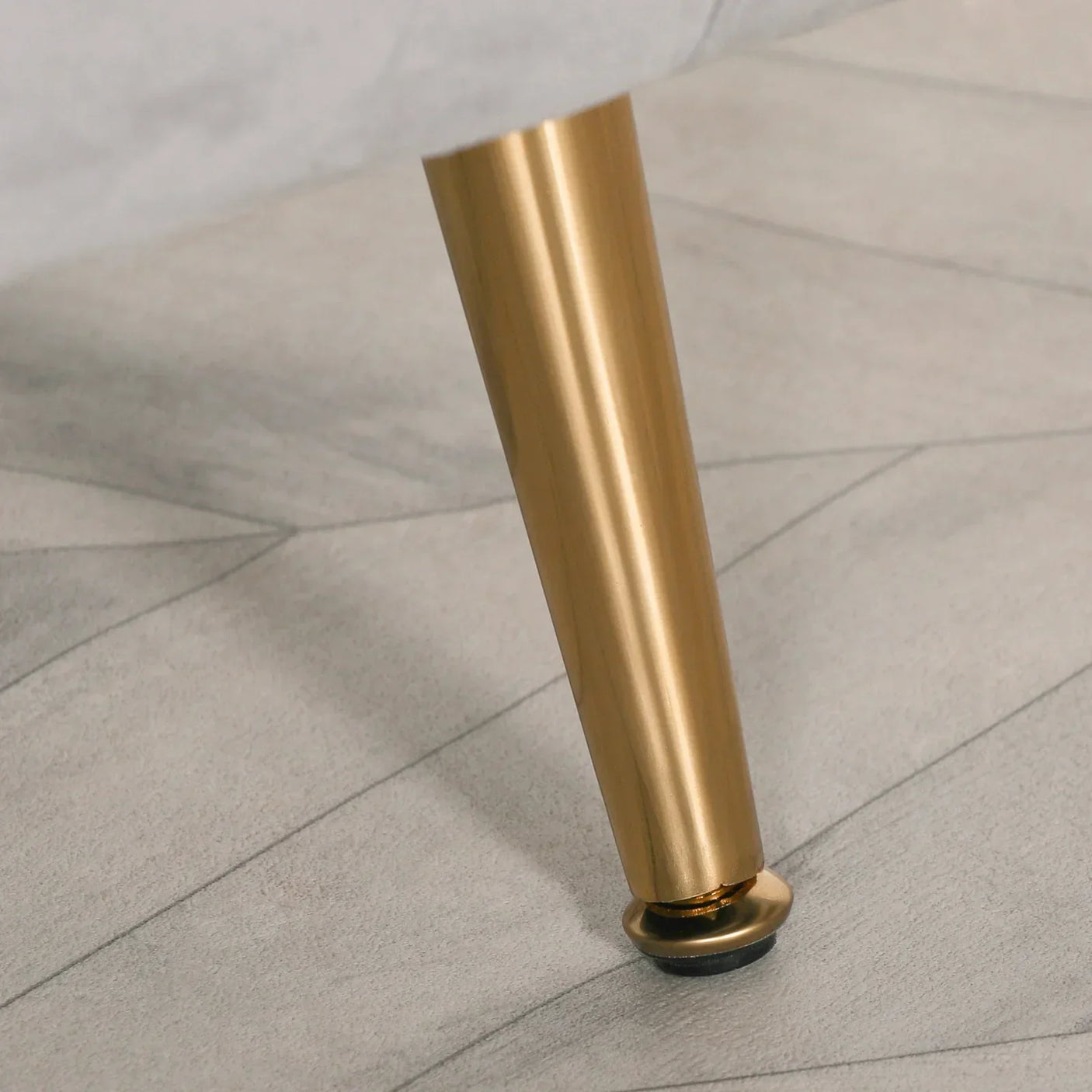 Gold metal furniture leg attached to upholstered sofa on light fabric flooring