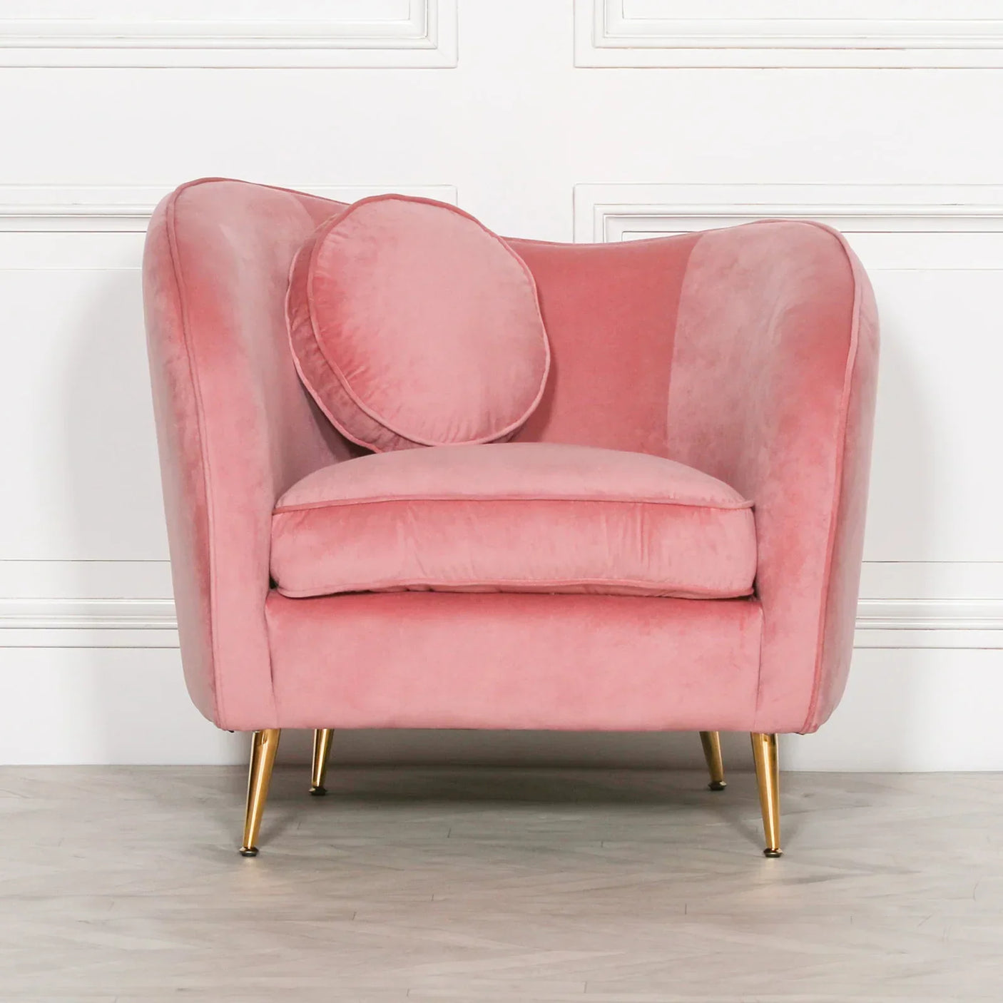 Pink velvet accent chair with gold legs and round cushion in modern living room