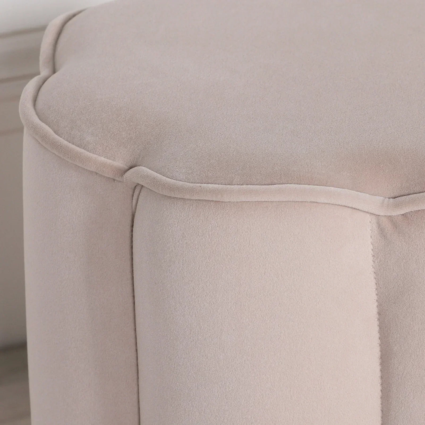Beige velvet ottoman with piped edge detail, close-up of textured upholstery