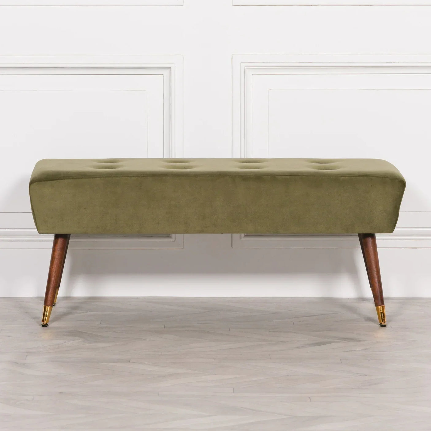 Olive green velvet bench with tufted seat and angled wooden legs on herringbone floor