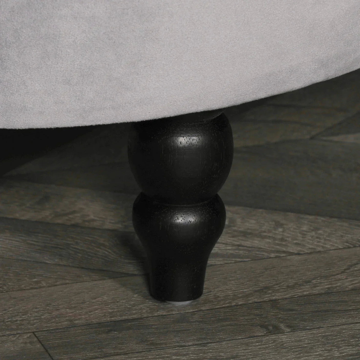 Closeup of dark wooden sofa leg on grey wood flooring