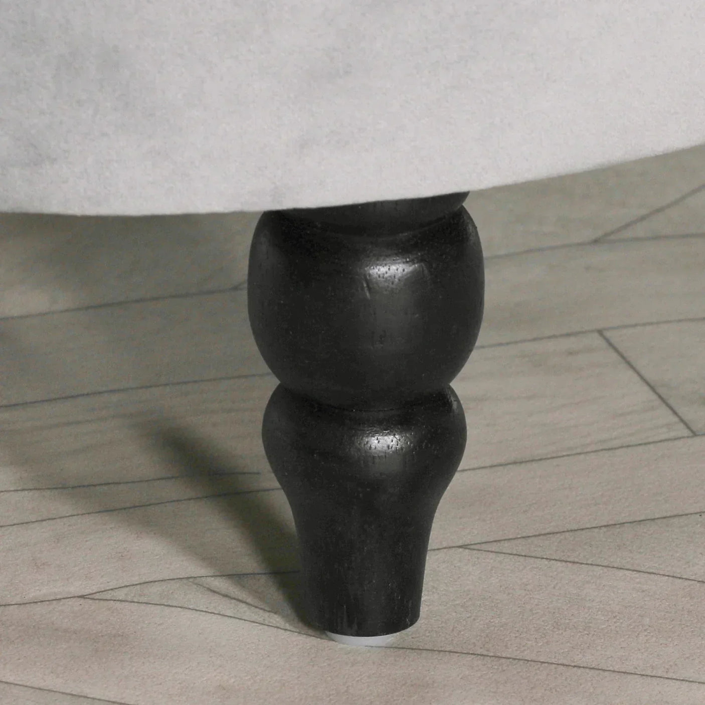 Black wooden sofa leg detail on light wood flooring