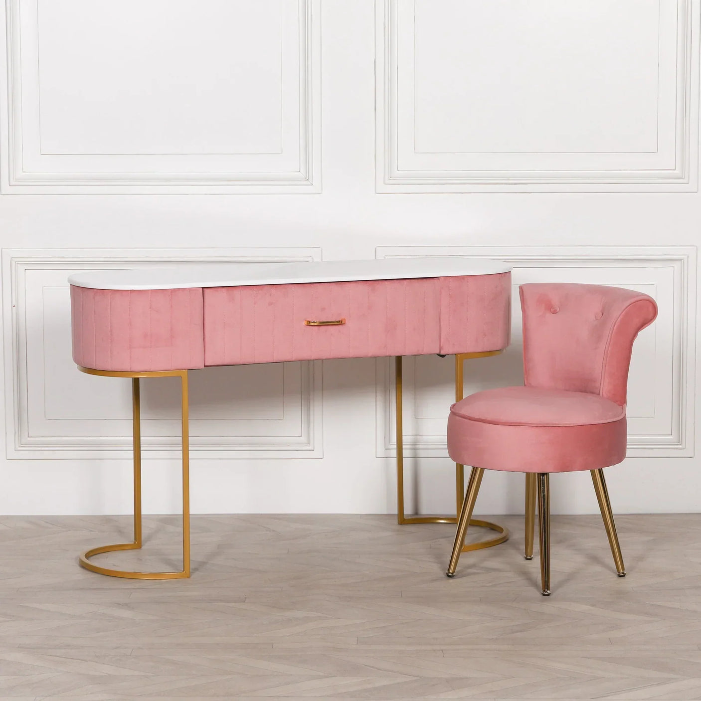 Pink velvet dressing table with gold legs and matching pink chair on wood floor