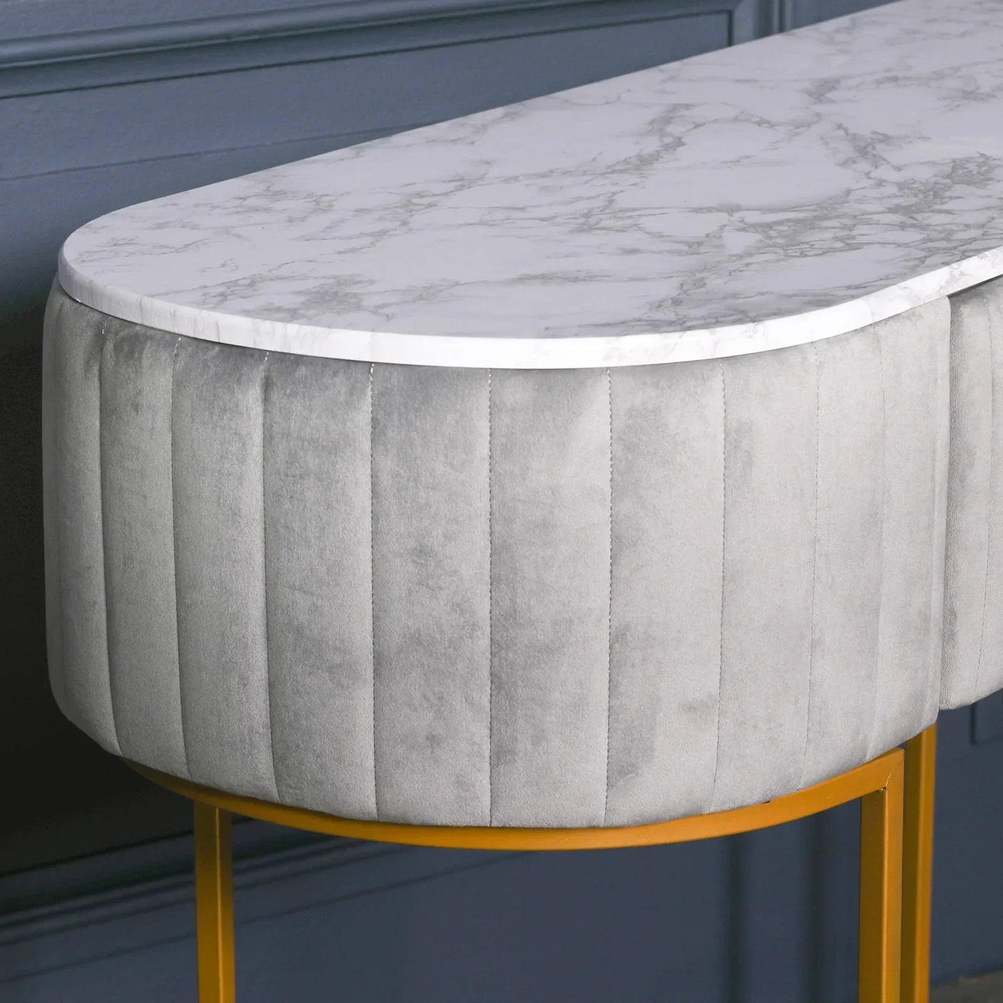 Marble top console table with vertical grey velvet panels and gold metal legs
