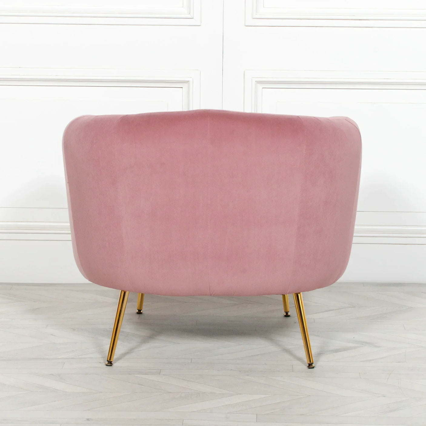 Back view of pink velvet accent chair with gold legs on light wood floor