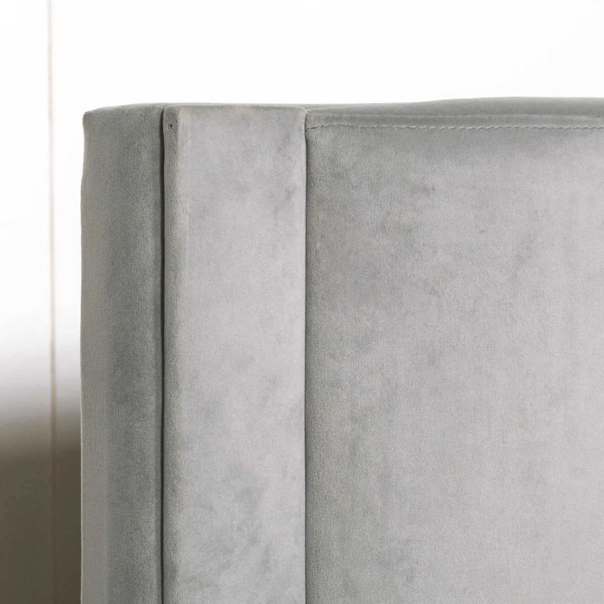 Closeup of grey velvet bed headboard with soft fabric texture and clean stitching