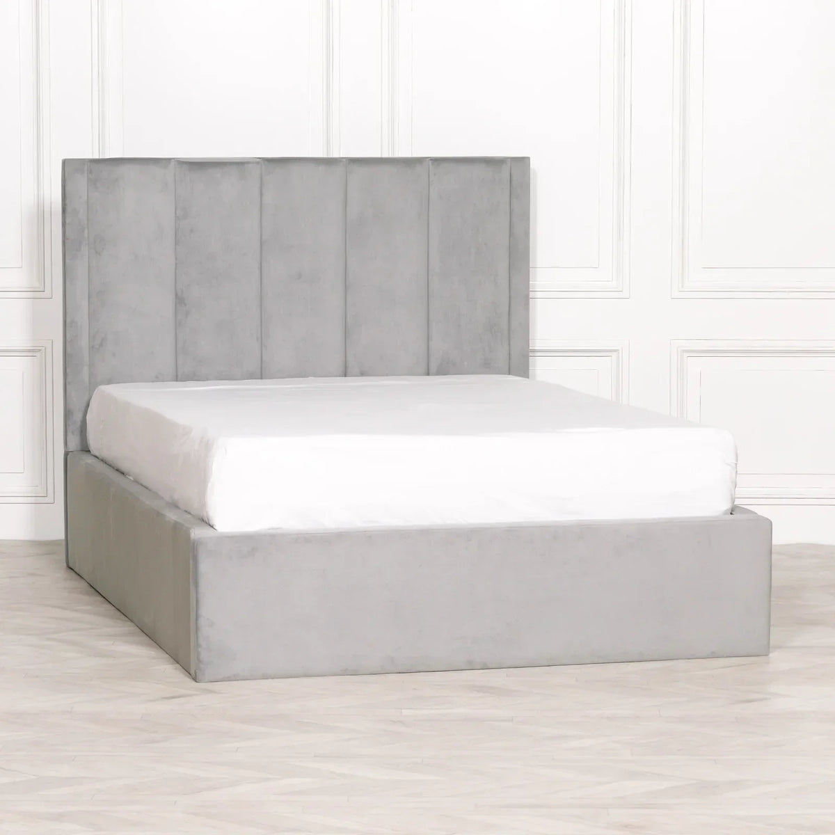 Grey velvet bed frame with vertical panel headboard and white mattress in minimal room