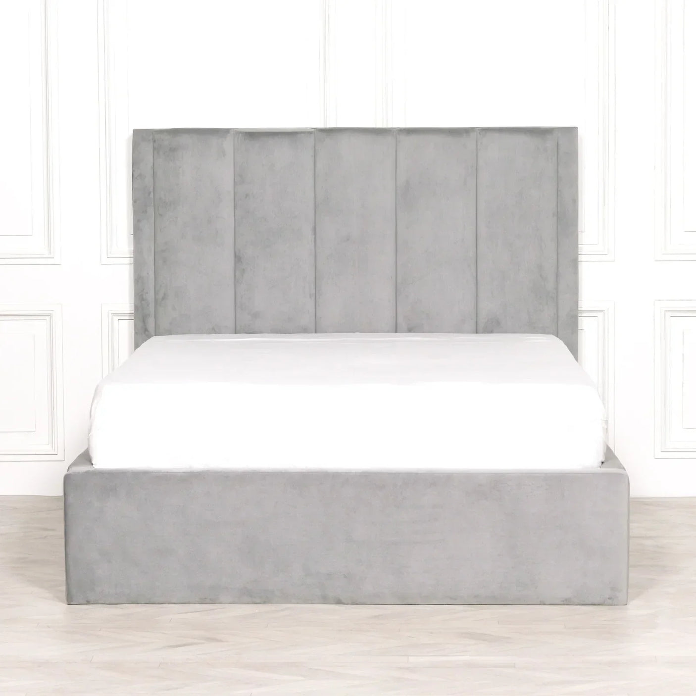 Grey upholstered bed frame with vertical panel headboard and low footboard on wood floor