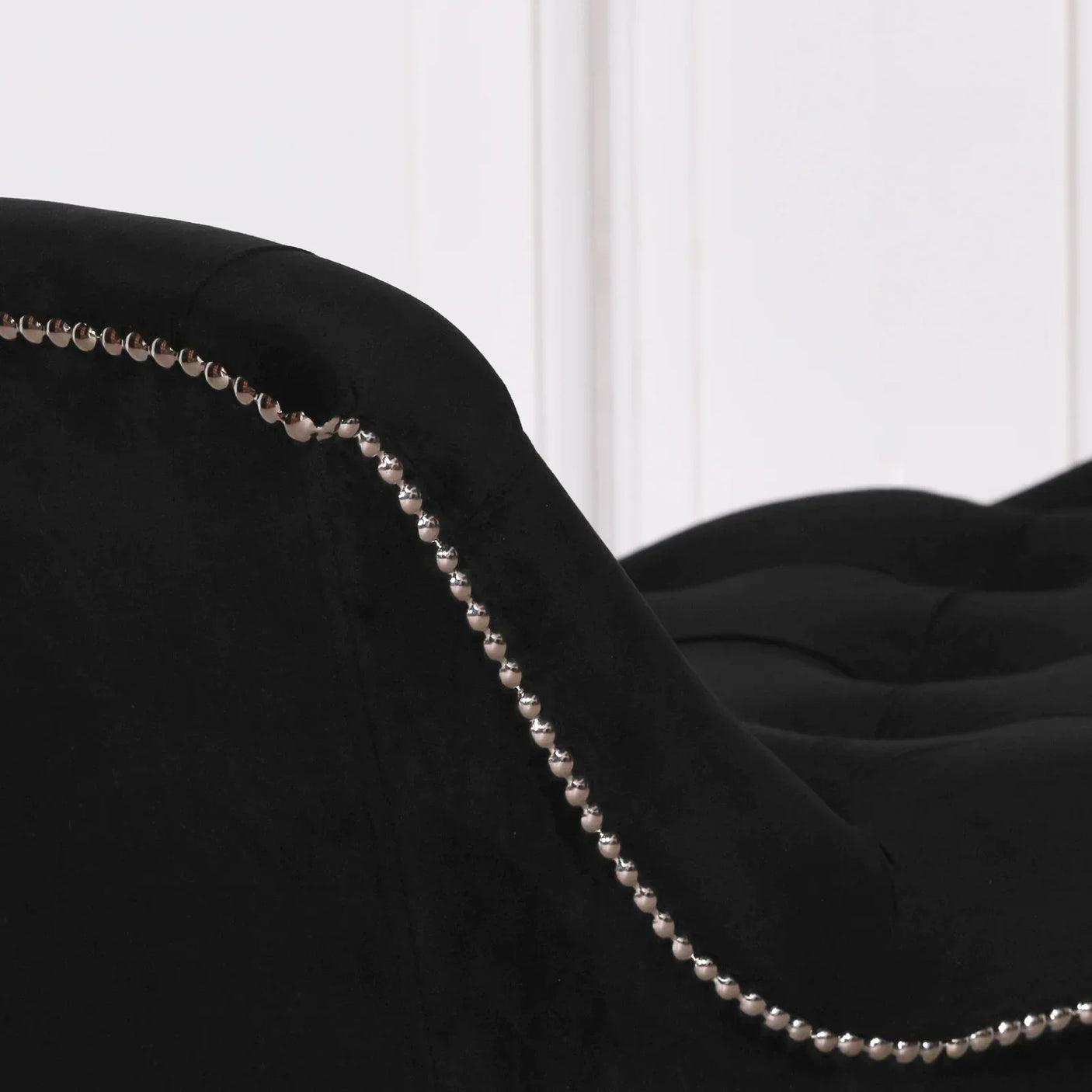 Black velvet sofa arm with button trim and tufted upholstery close-up