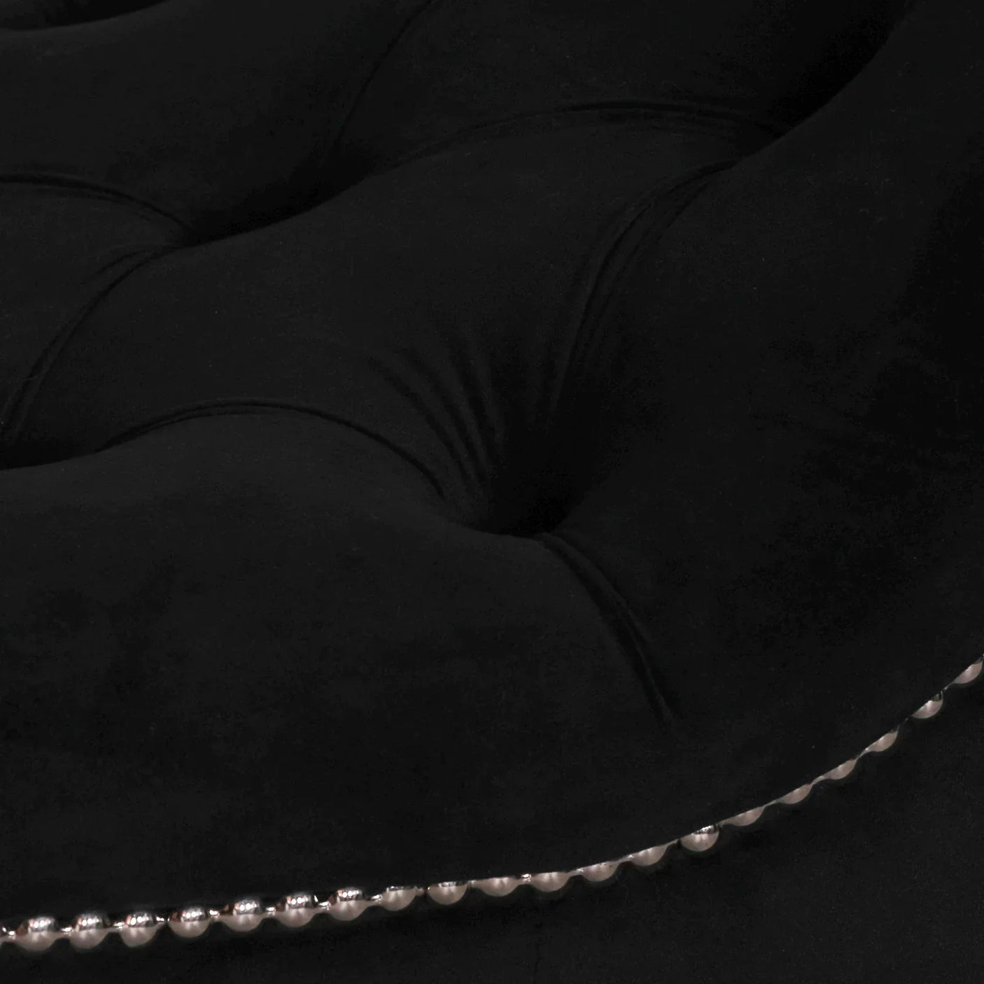 Black velvet tufted sofa cushion with silver stud detailing close-up