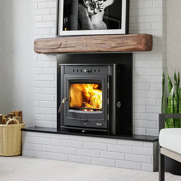 Black wood burning stove inset in a white brick fireplace with wooden mantel