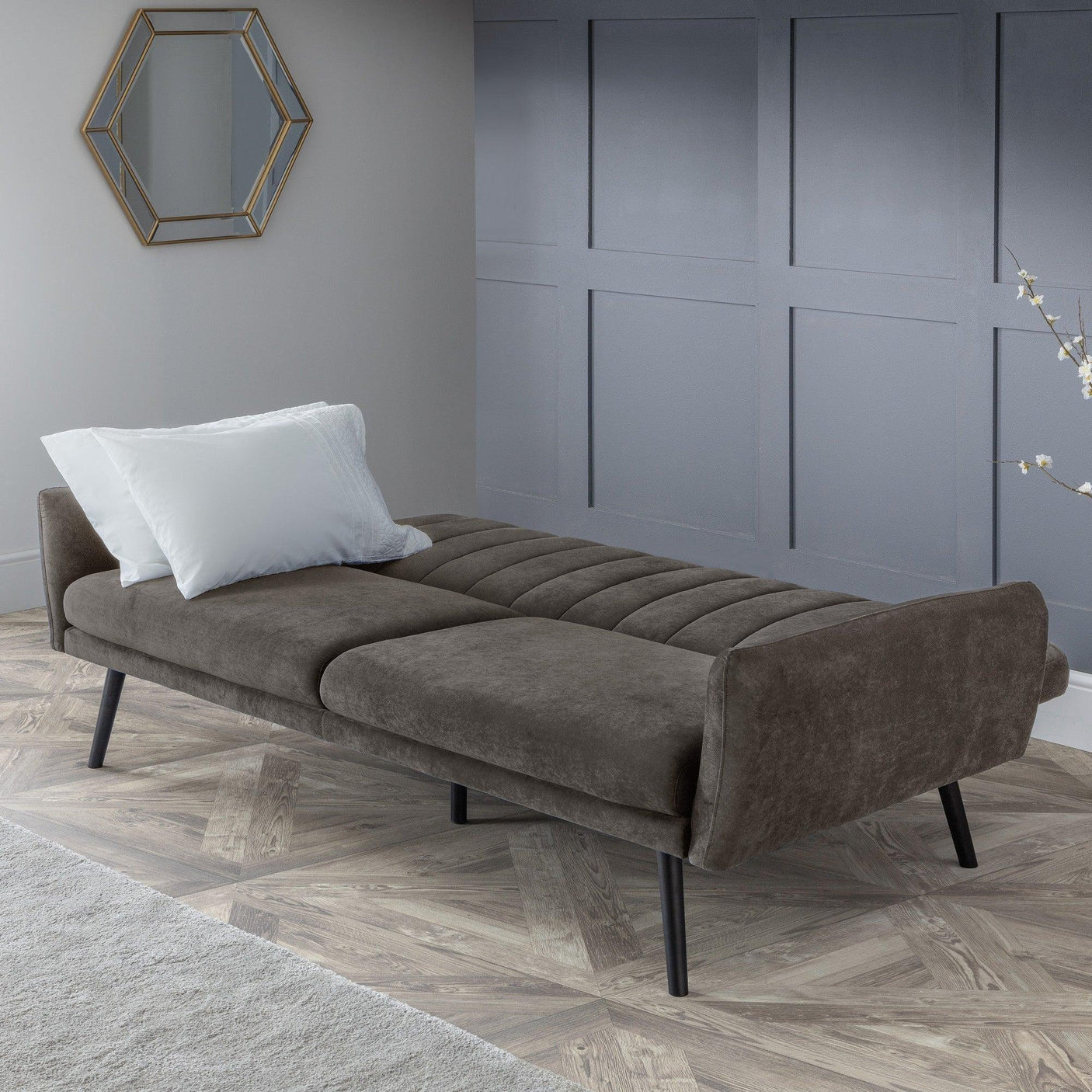 Grey sofabed open with white pillow in modern living room with panelled wall