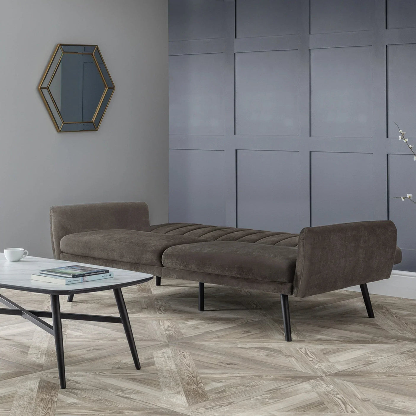 Grey sofabed fully extended in modern living room with parquet flooring and coffee table
