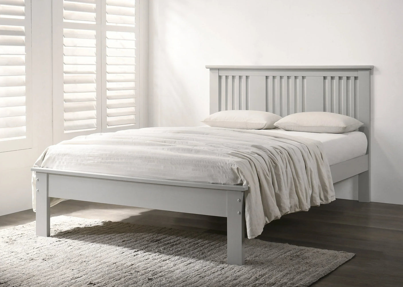 Grey wooden bed frame with slatted headboard and white bedding in bright bedroom