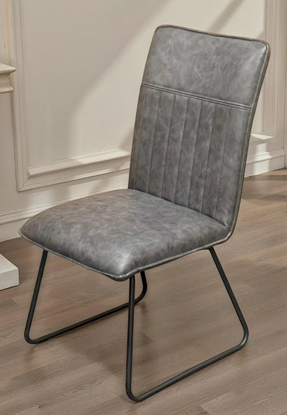 Grey faux leather dining chair with metal sled legs on wood floor