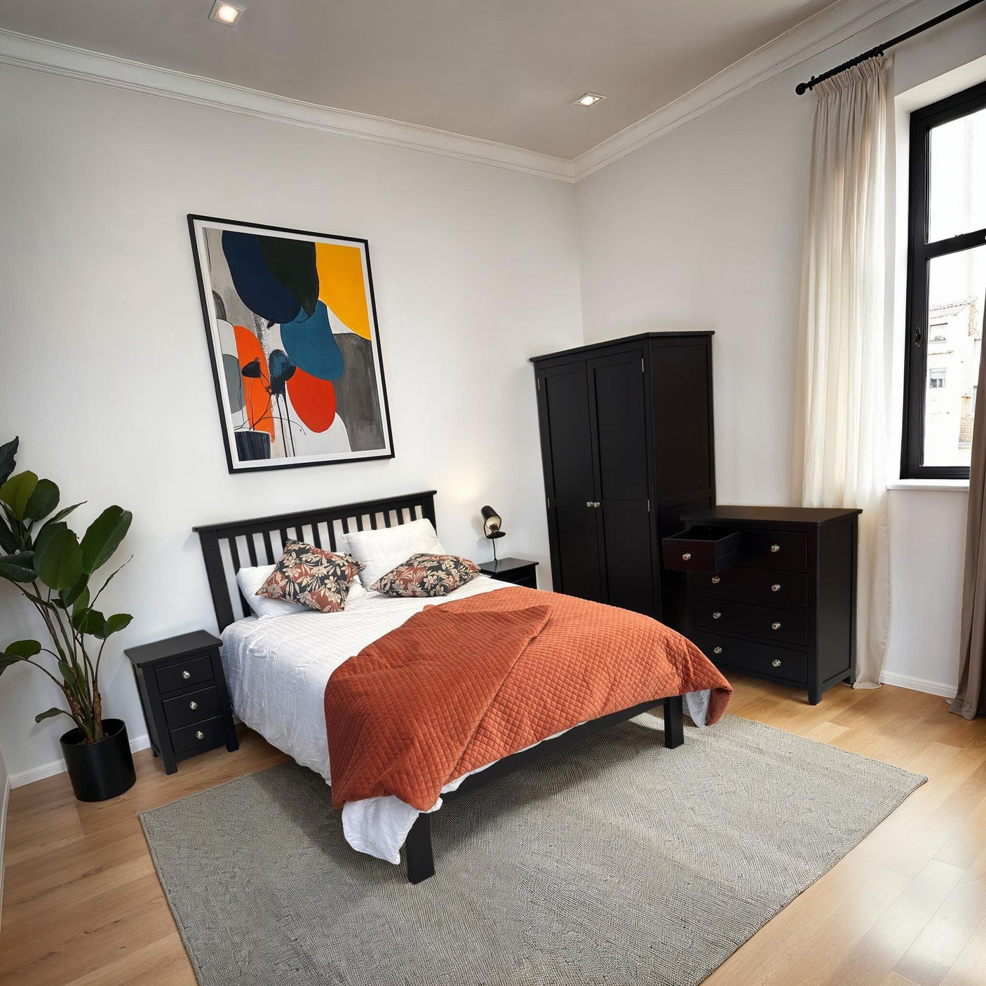 Black wooden bed frame with orange throw, matching wardrobe and drawers in modern bedroom