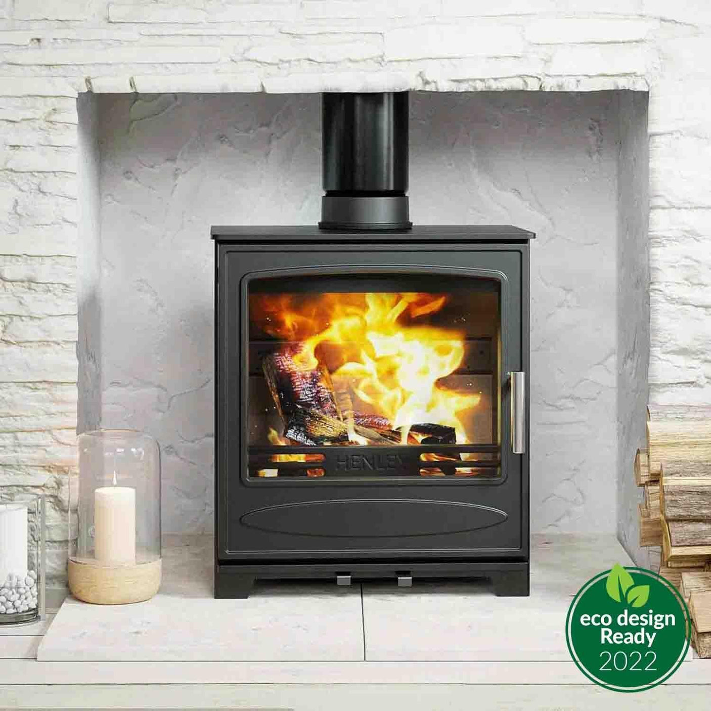 Black eco wood burning stove with glass door in stone fireplace, burning logs visible inside