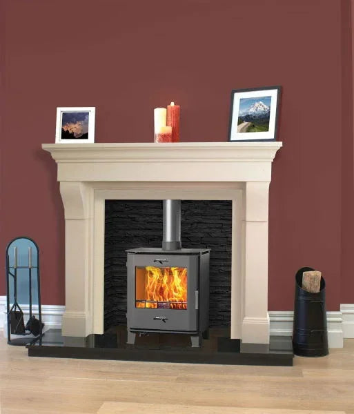 Cream fireplace with wood burning stove, black stone surround, and accessories on hardwood floor