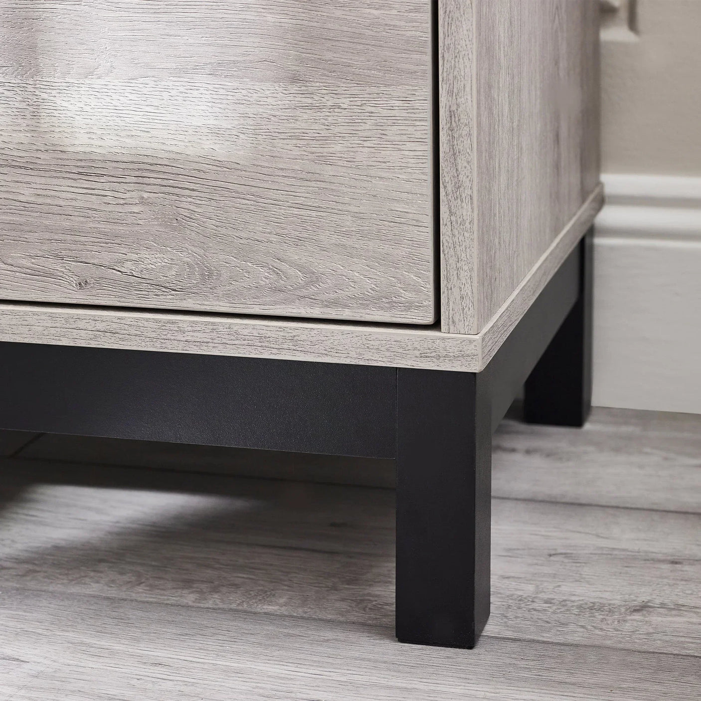 Grey oak chest of drawers close-up showing wood grain and black metal legs