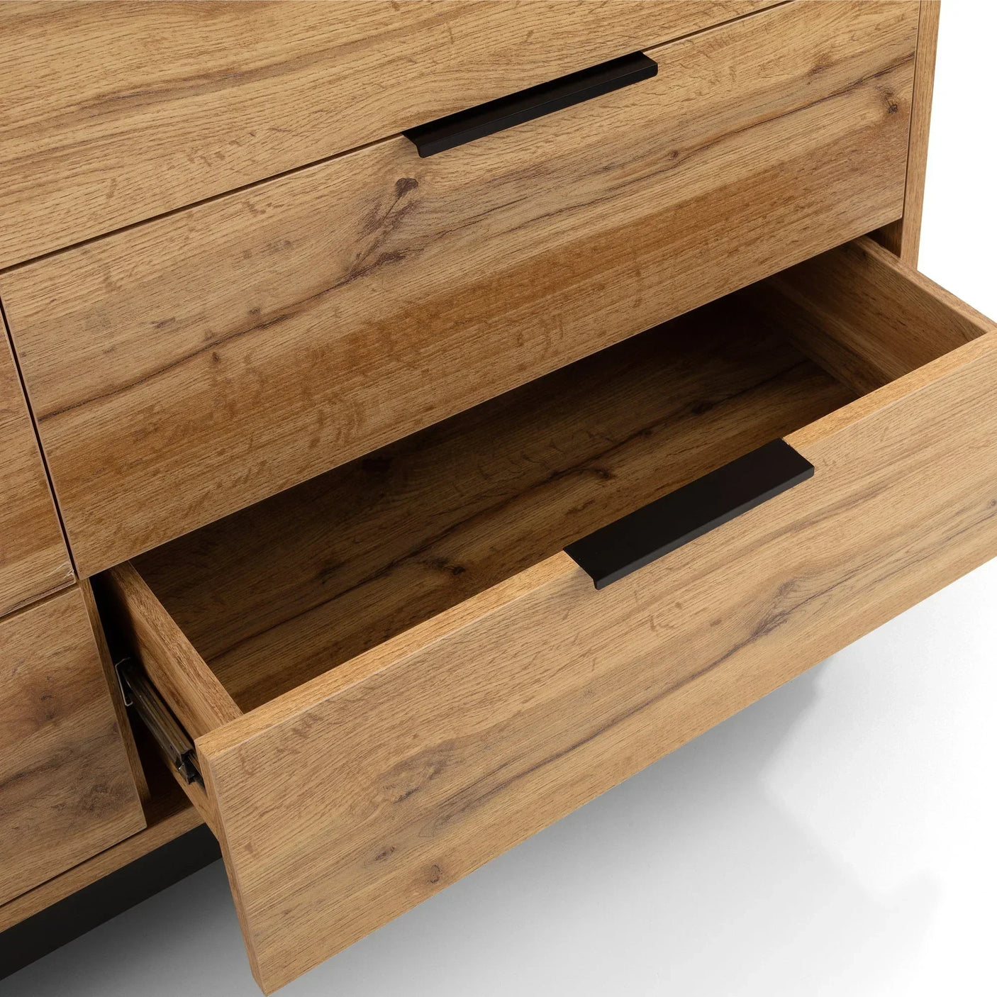 Close-up of oak chest of drawers with two open drawers and black metal handles