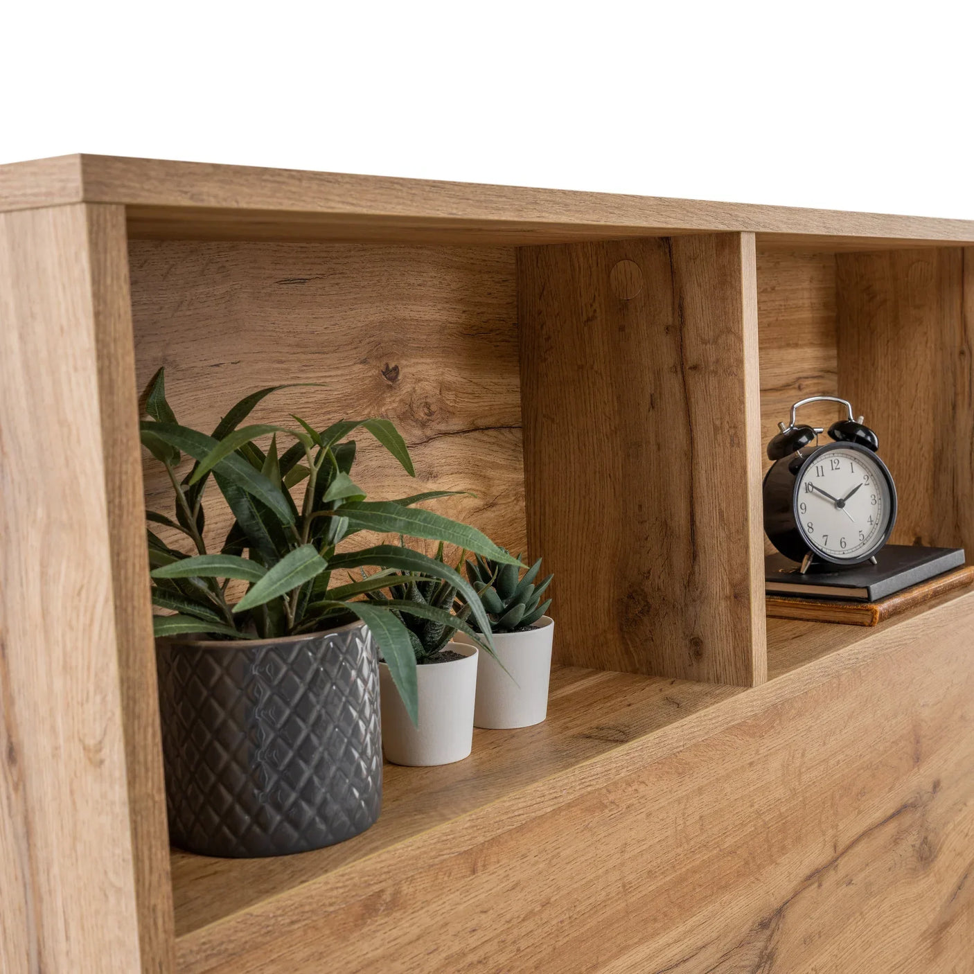 Oak finish double bed headboard shelf with potted plants and alarm clock styled