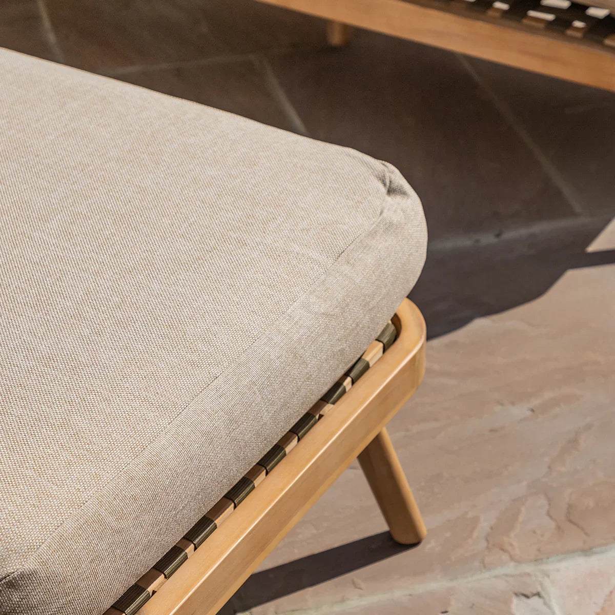 Beige outdoor sofa cushion on wooden frame with woven support detail