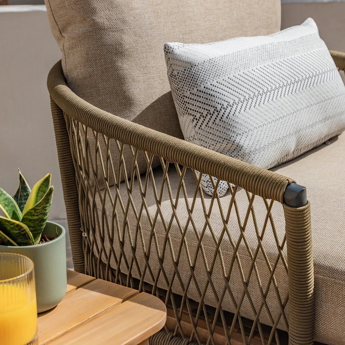 Close-up of beige outdoor sofa with rope arm detail and patterned cushion