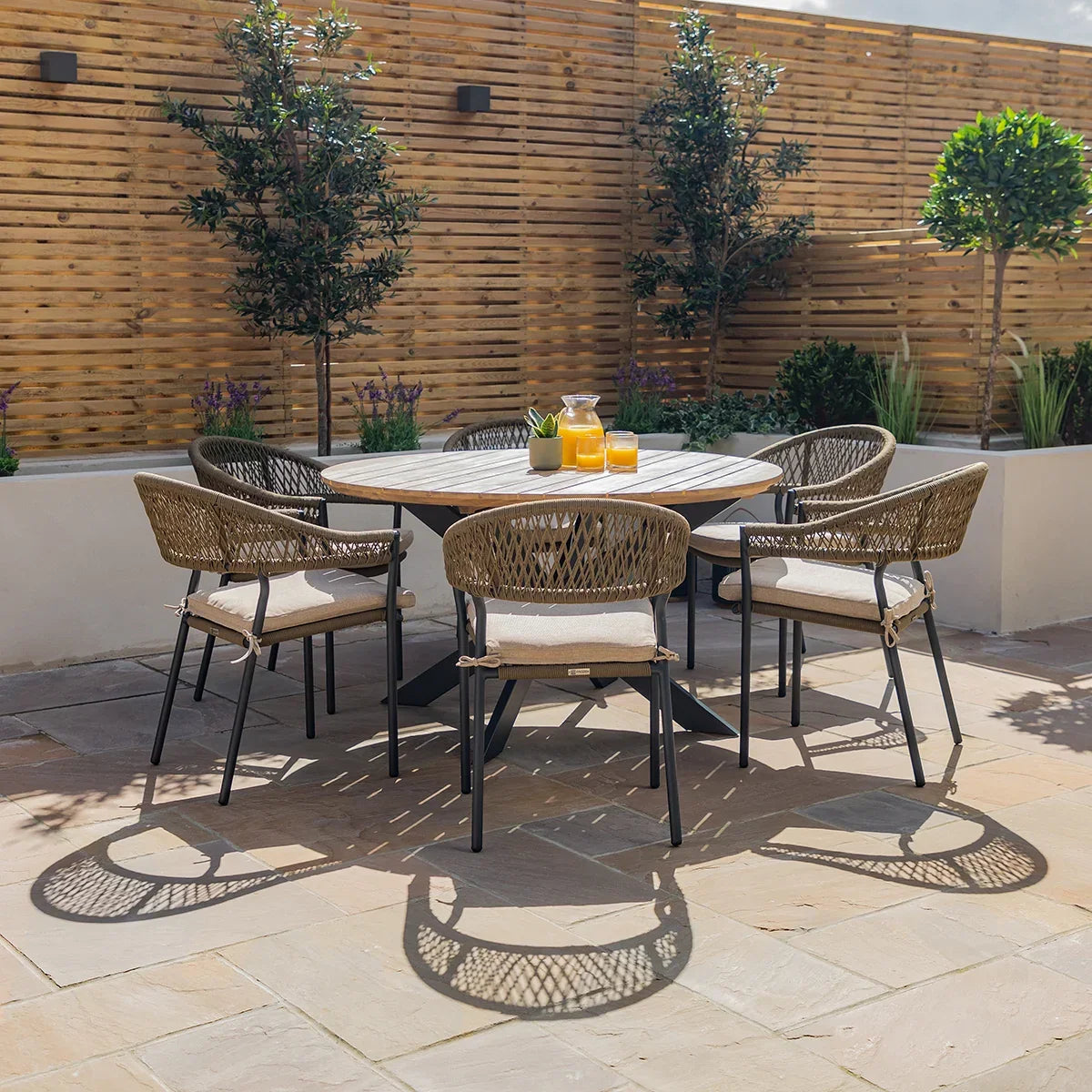 Rattan outdoor dining set with round table and four cushioned chairs on patio