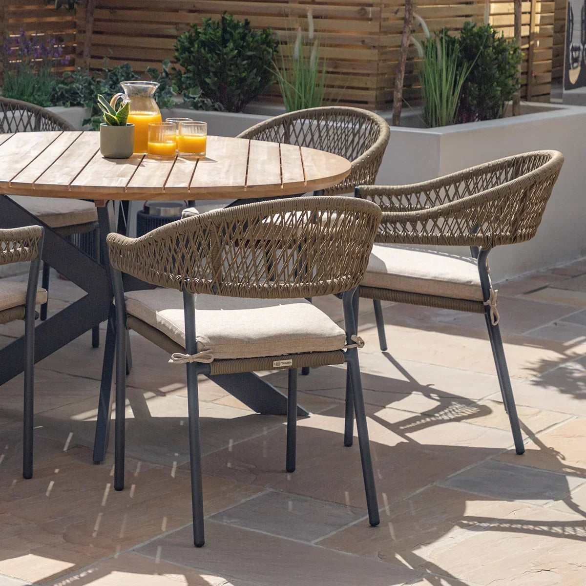 Rattan garden dining chair with cushion and metal legs around wooden outdoor table