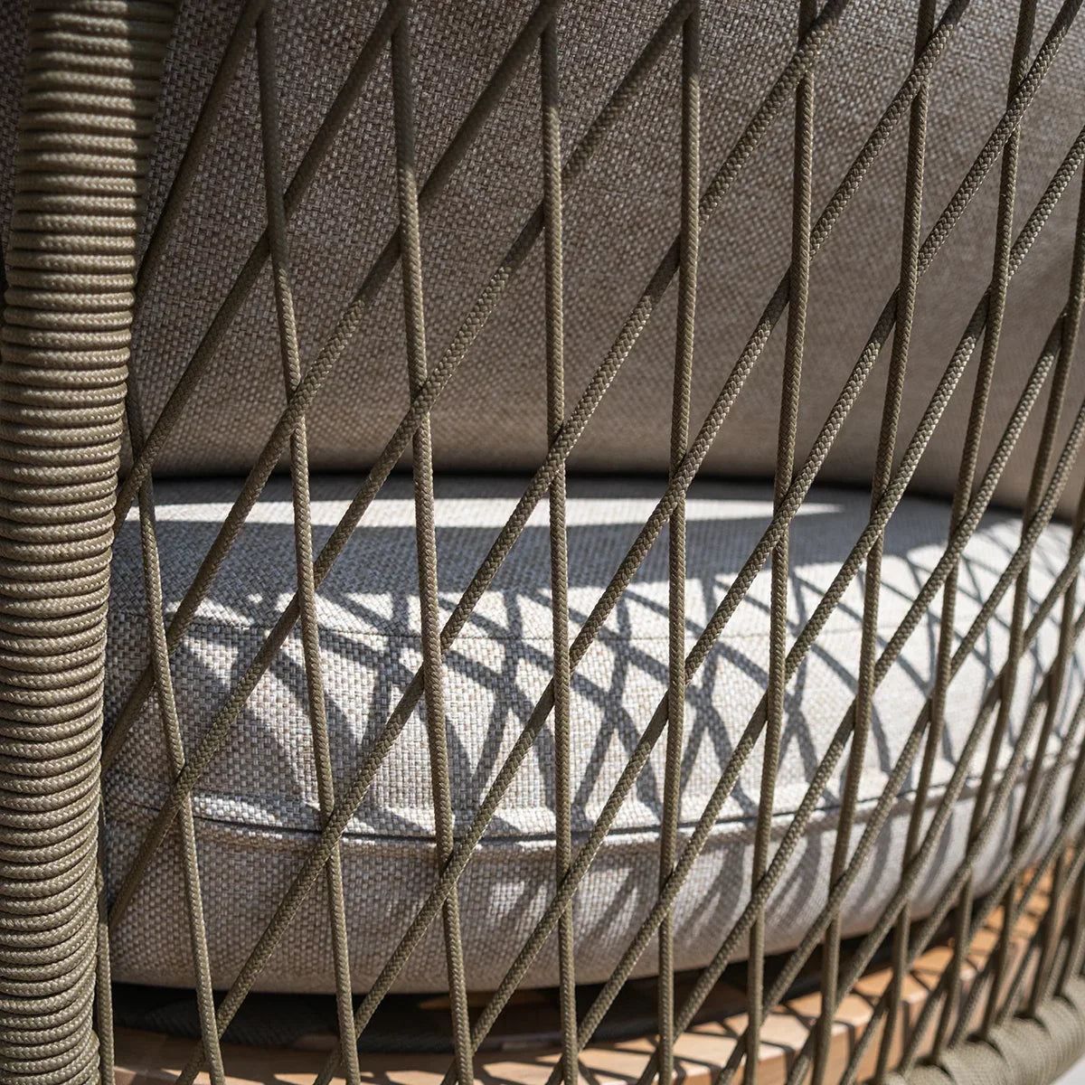 Close up of garden sofa with beige cushion and woven rope detailing on armrest