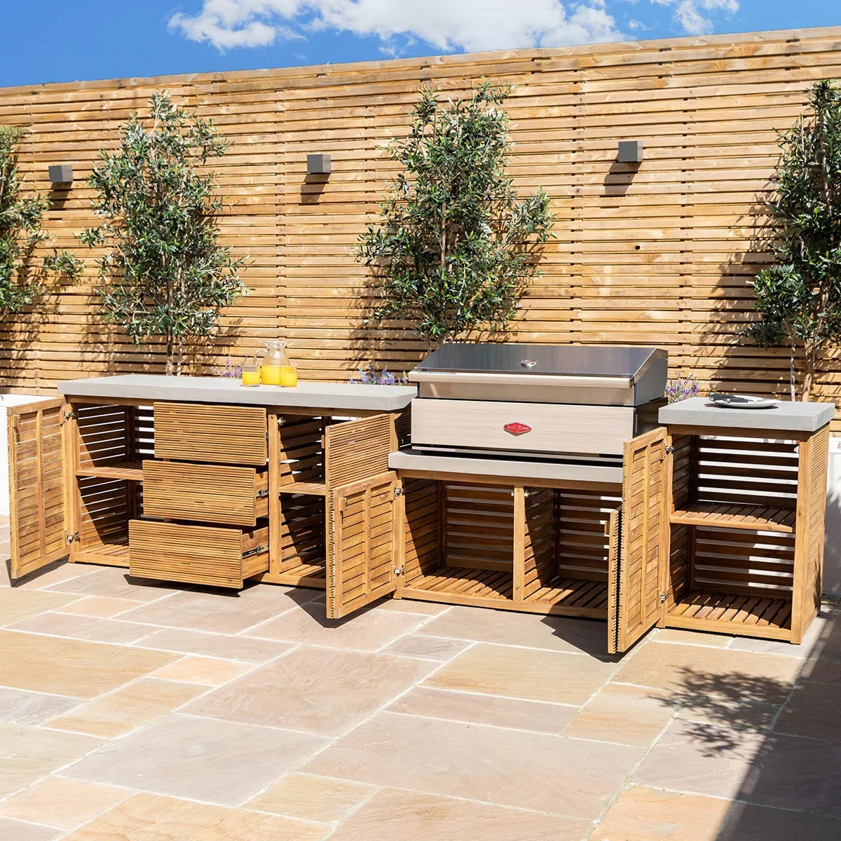 Outdoor kitchen with wooden storage units and barbecue on stone patio